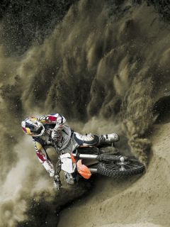 Мотогонщик в песчаном повороте