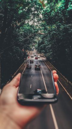 Съемка в принудительном ракурсе автомобилей, движущихся по дороге под смартфоном