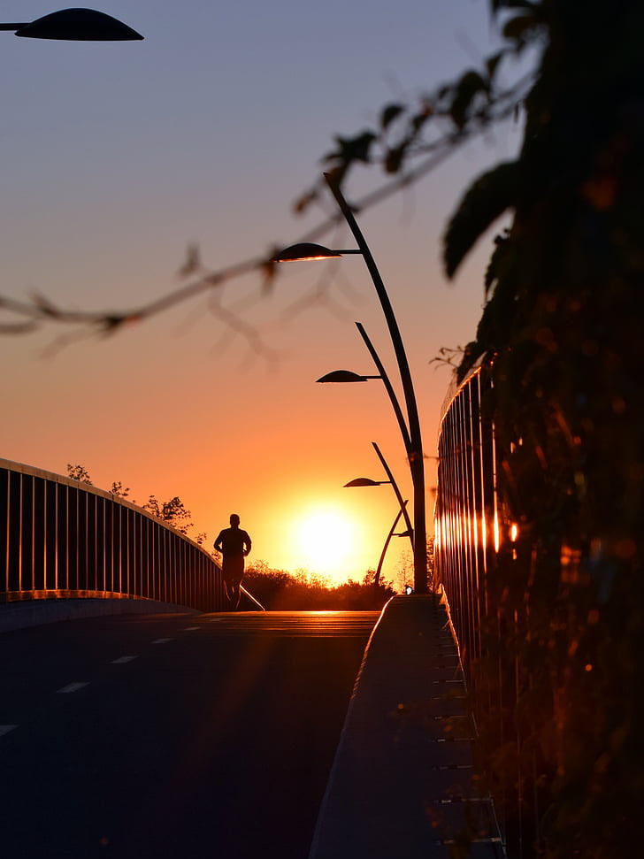 Бегущий парень на мосту при закате