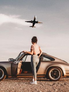 Девушка у авто и пролетающий самолёт