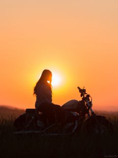Женский силуэт на мотоцикле при закате
