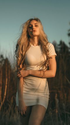 Блондинка в белом платье на вечернем Солнце