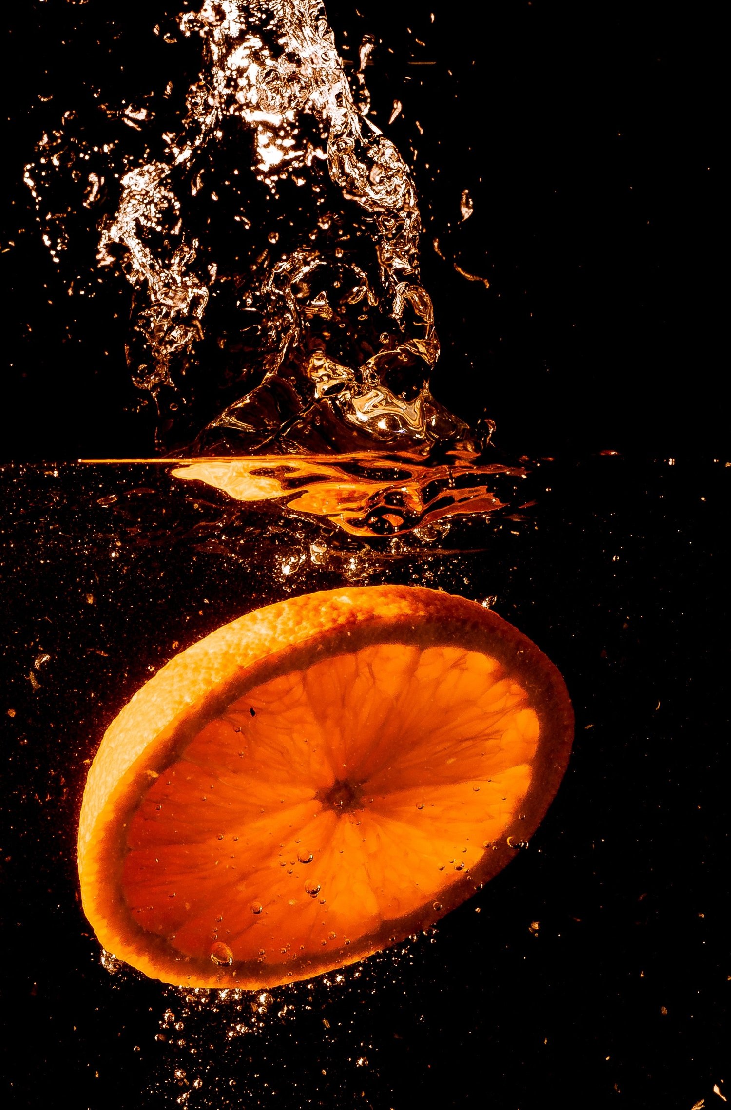 Апельсин в воде на черном фоне