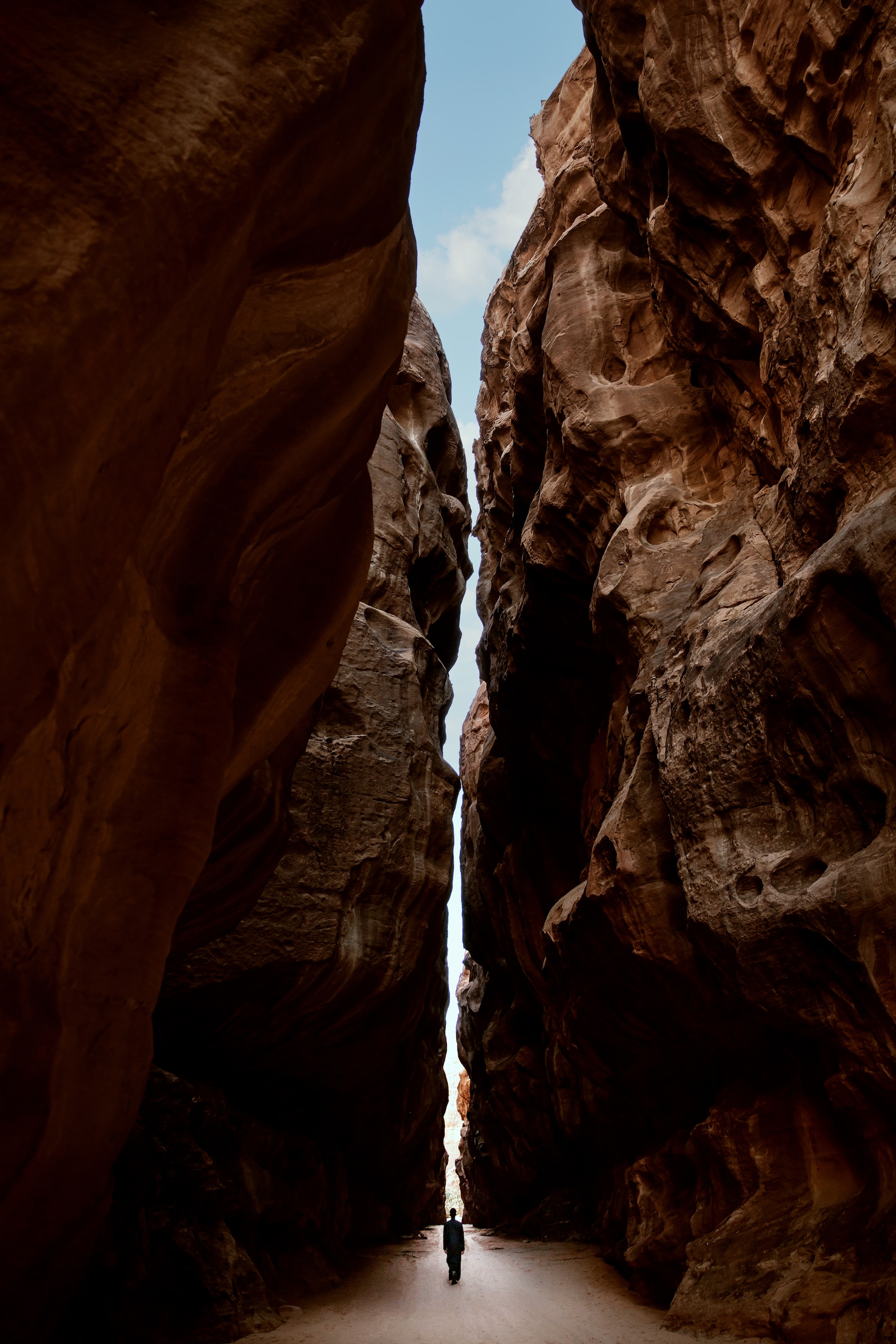 Человек, идущий через узкую щель в каньоне