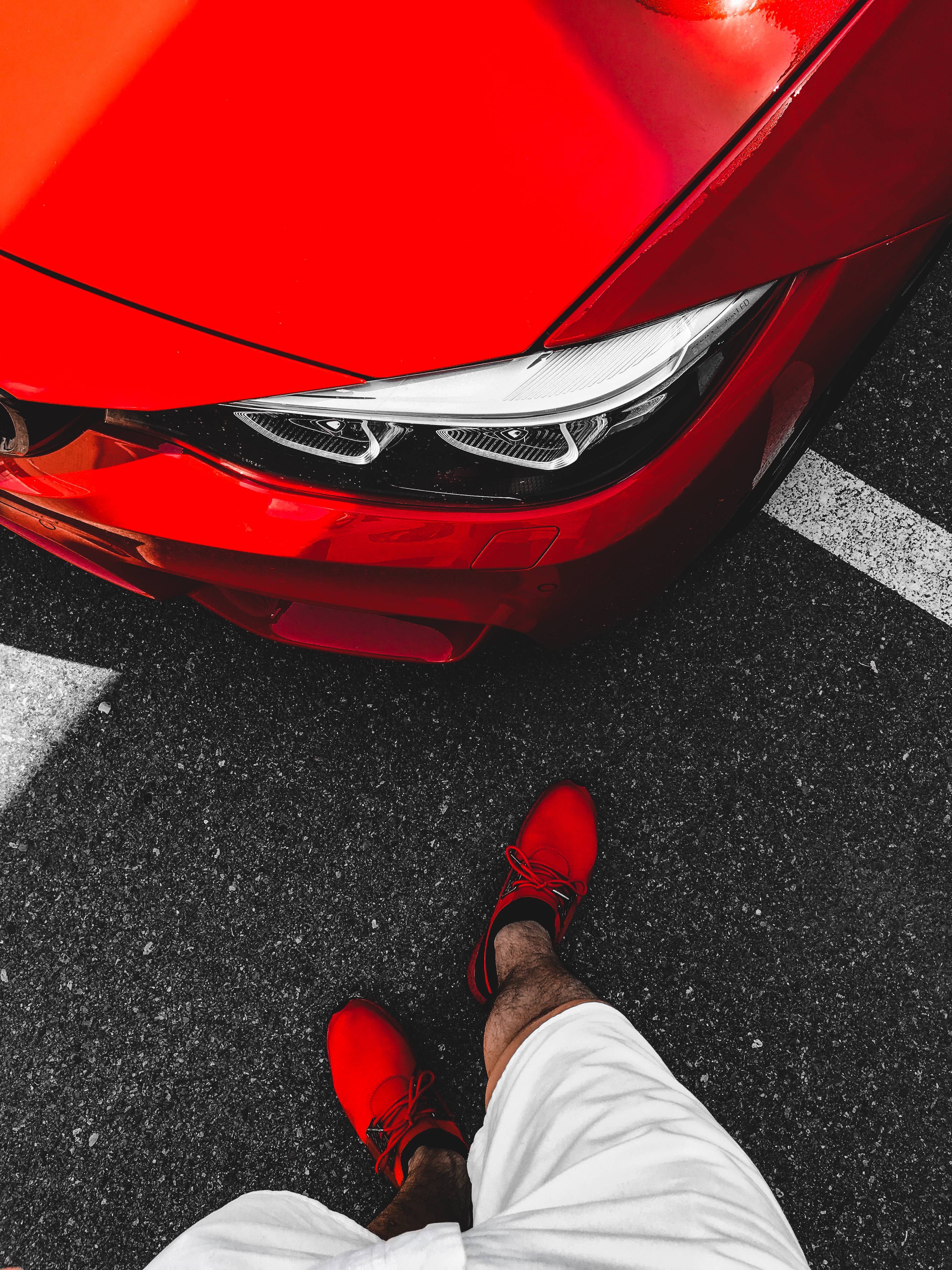 Мужчина в красных ботинках, стоящий перед Ferrari-Красное фото BMW