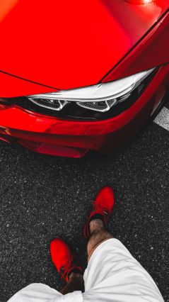 Мужчина в красных ботинках, стоящий перед Ferrari (Красное фото BMW)